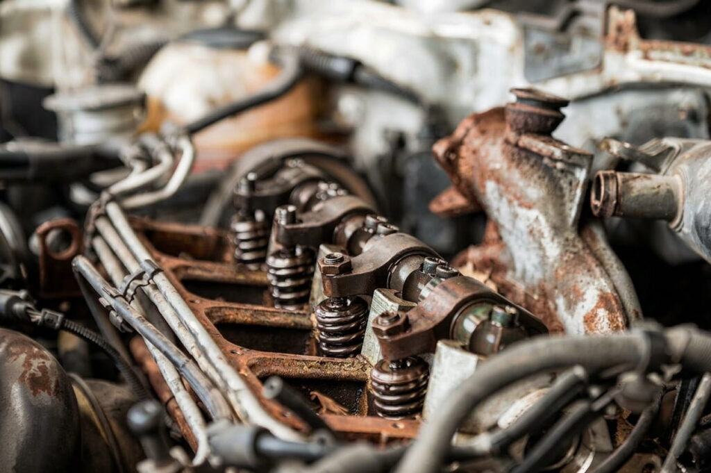 Close-up macro shot of a corroded car engine block, used as a mechanical analogy for technical debt and digital decay in bespoke web engineering.